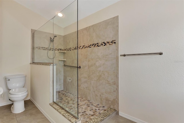 bathroom featuring toilet, tile patterned floors, and tiled shower