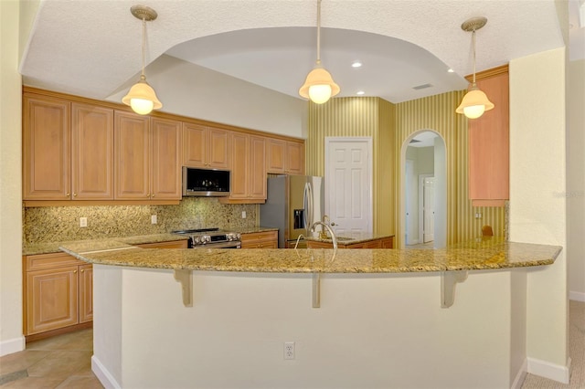 kitchen featuring kitchen peninsula, hanging light fixtures, and appliances with stainless steel finishes