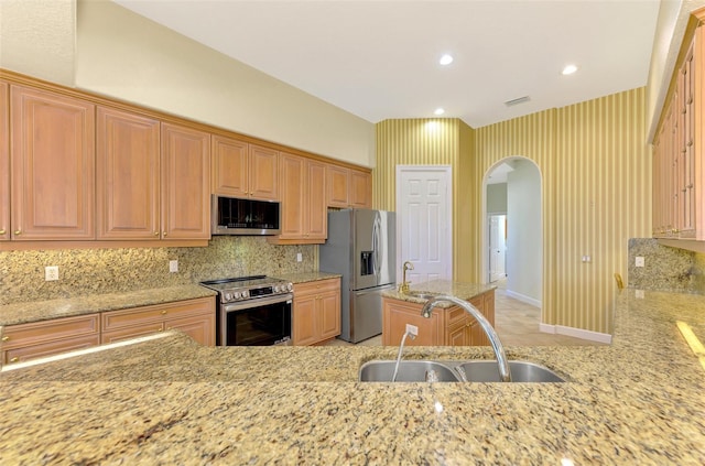 kitchen with sink, light stone countertops, tasteful backsplash, kitchen peninsula, and stainless steel appliances