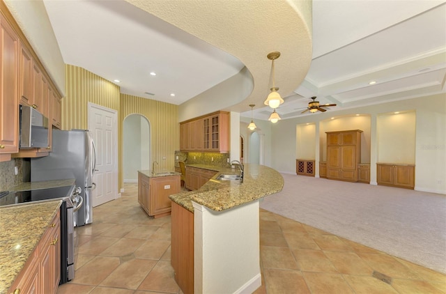 kitchen with stainless steel appliances, tasteful backsplash, kitchen peninsula, decorative light fixtures, and light carpet