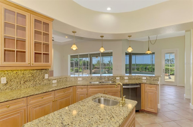 kitchen featuring dishwasher, light stone counters, sink, and hanging light fixtures