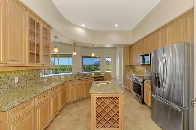 kitchen featuring sink, hanging light fixtures, light stone countertops, an island with sink, and stainless steel appliances