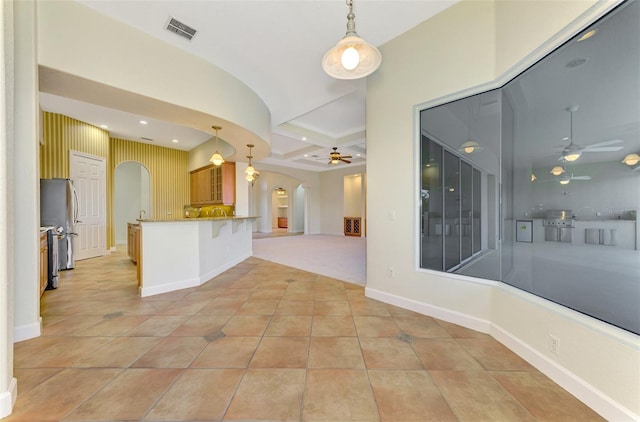 interior space with pendant lighting, a breakfast bar, kitchen peninsula, and stainless steel refrigerator