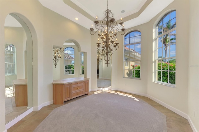 interior space with crown molding, a wealth of natural light, a notable chandelier, and light tile patterned flooring