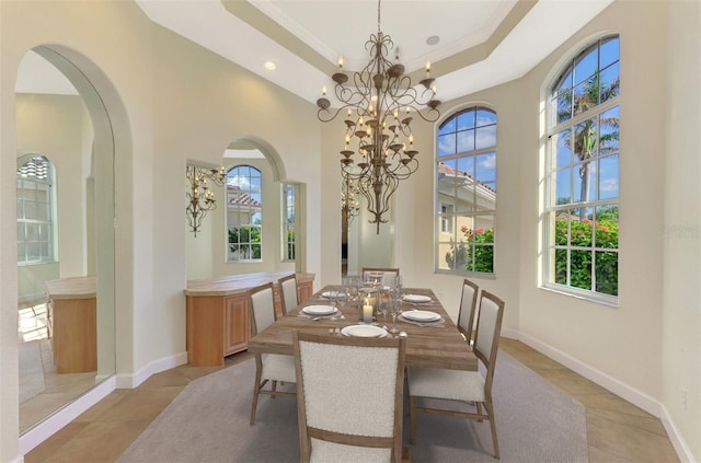 tiled dining area with a wealth of natural light, a chandelier, a high ceiling, and ornamental molding