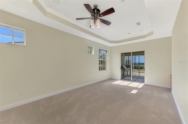 unfurnished room featuring a tray ceiling, ceiling fan, light colored carpet, and ornamental molding