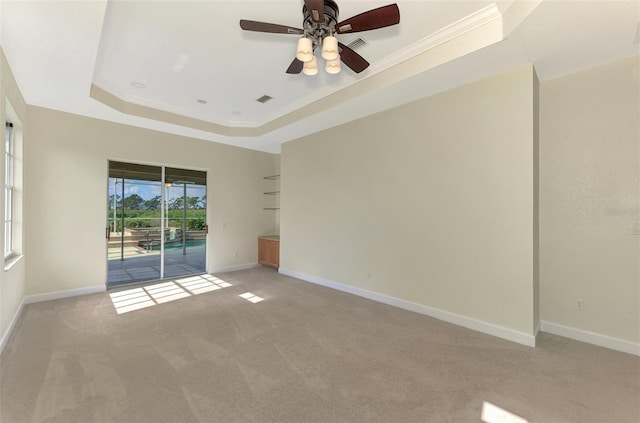 carpeted spare room featuring ceiling fan, a raised ceiling, and crown molding