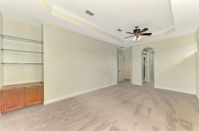 carpeted spare room with a tray ceiling, ceiling fan, and crown molding