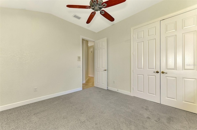 unfurnished bedroom featuring light carpet, a closet, vaulted ceiling, and ceiling fan