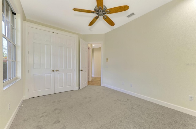 unfurnished bedroom with light carpet, a closet, and ceiling fan