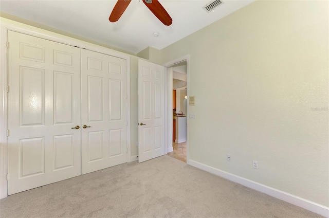 unfurnished bedroom with ceiling fan, light colored carpet, and a closet