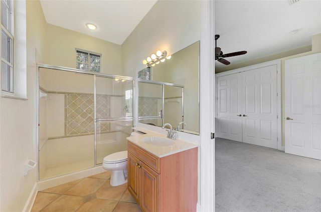 bathroom featuring ceiling fan, tile patterned flooring, toilet, vanity, and a shower with shower door