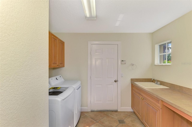 laundry area featuring cabinets, a textured ceiling, sink, light tile patterned floors, and washing machine and dryer