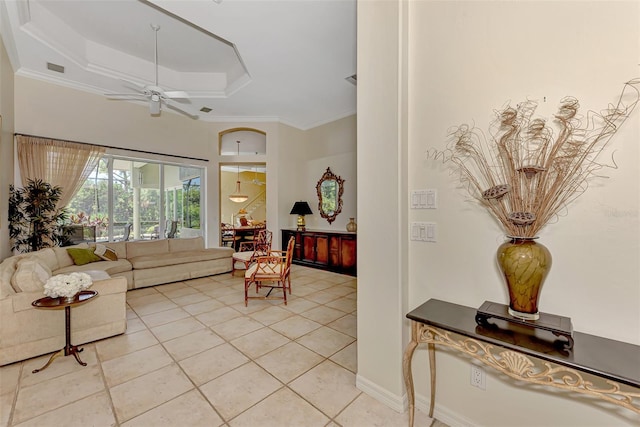 living room with ceiling fan, light tile patterned flooring, crown molding, and a tray ceiling