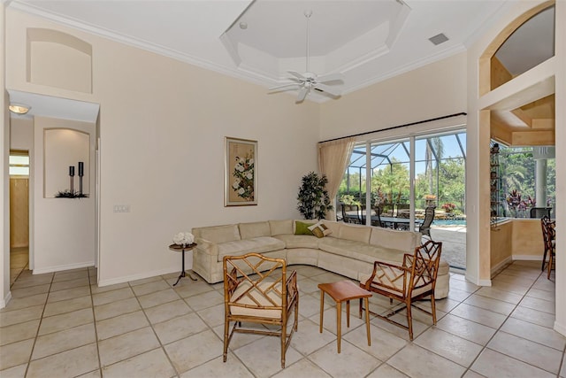 tiled living room featuring a towering ceiling, a raised ceiling, ceiling fan, and crown molding