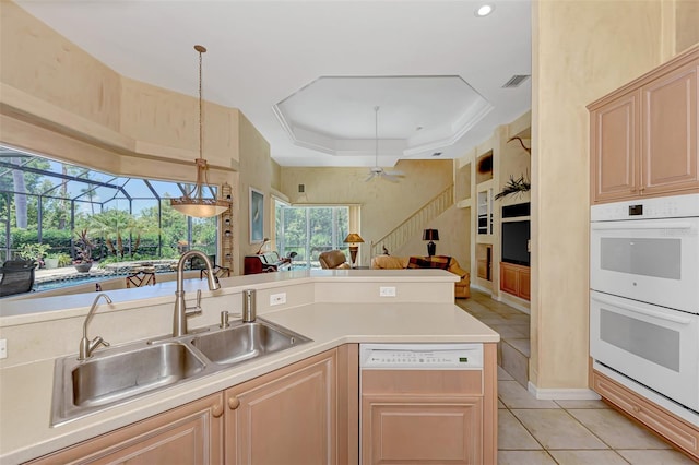 kitchen with white appliances, sink, hanging light fixtures, ceiling fan, and light brown cabinetry