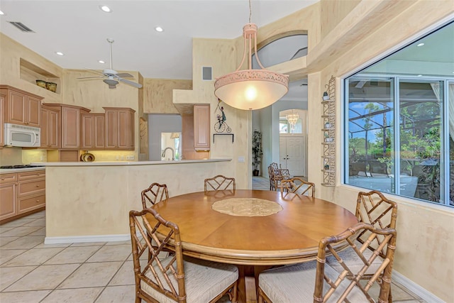 dining room with ceiling fan, light tile patterned flooring, and a high ceiling