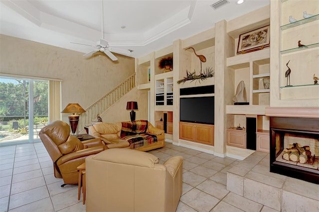 tiled living room featuring ceiling fan, a raised ceiling, and built in features