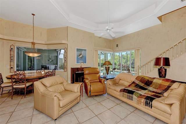 tiled living room with a tray ceiling, ceiling fan, and a high ceiling