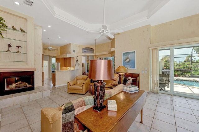 tiled living room featuring ceiling fan, a raised ceiling, and a towering ceiling