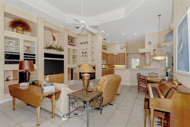 living room with a raised ceiling, built in shelves, crown molding, and light tile patterned floors