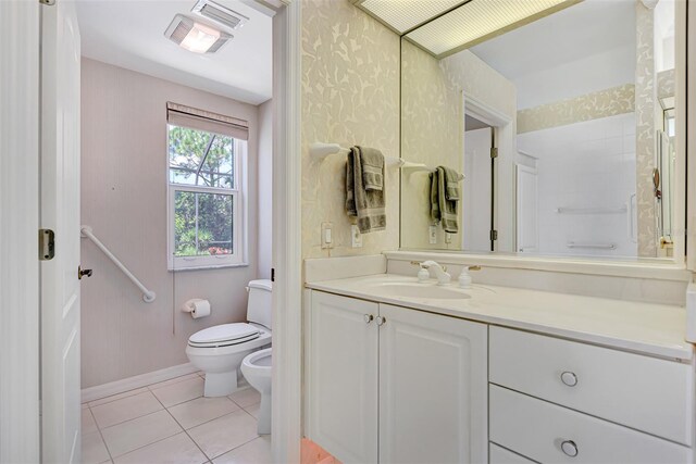 bathroom featuring tile patterned flooring, vanity, toilet, and a bidet