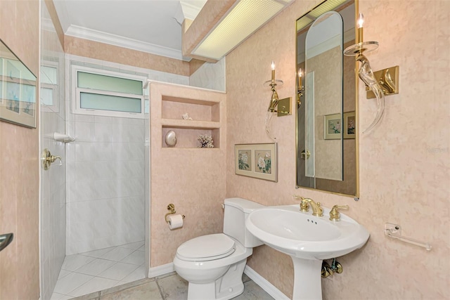 bathroom featuring tile patterned floors, toilet, crown molding, and a tile shower