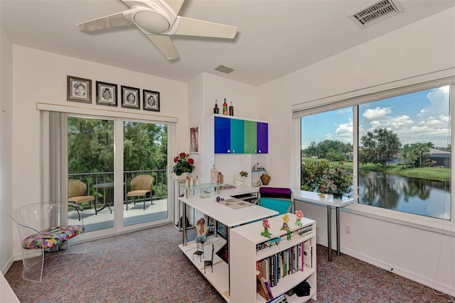 office space with ceiling fan, a water view, and a healthy amount of sunlight