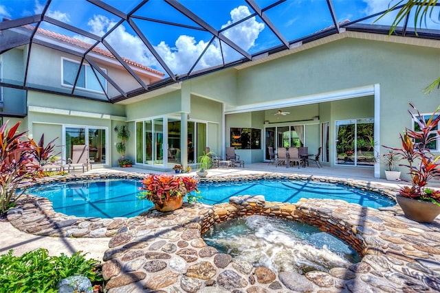 view of swimming pool featuring glass enclosure, ceiling fan, an in ground hot tub, and a patio