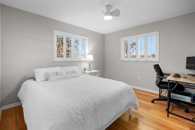 bedroom with hardwood / wood-style flooring, ceiling fan, and multiple windows