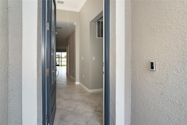 hallway featuring a textured wall, visible vents, baseboards, and ornamental molding