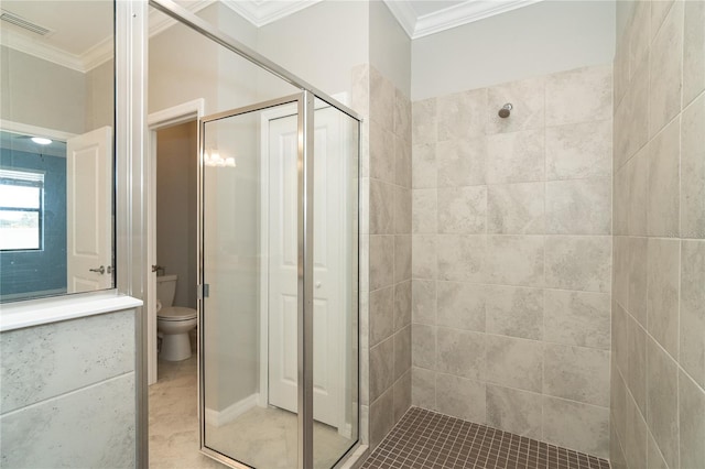 bathroom featuring toilet, a shower with door, and ornamental molding