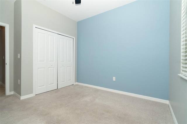 unfurnished bedroom with light carpet, ceiling fan, and a closet