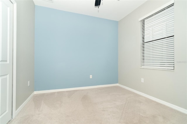 carpeted empty room with baseboards and a ceiling fan