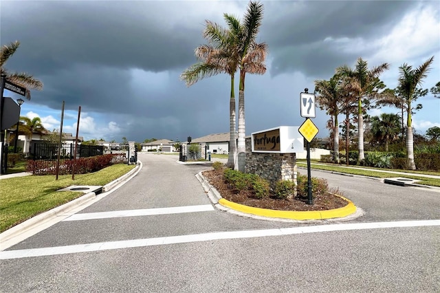 view of street with a gated entry, curbs, and traffic signs