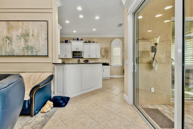 kitchen featuring light tile patterned flooring, white cabinetry, and ornamental molding