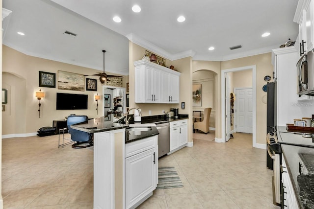 kitchen with appliances with stainless steel finishes, ornamental molding, a kitchen breakfast bar, dark stone counters, and white cabinets