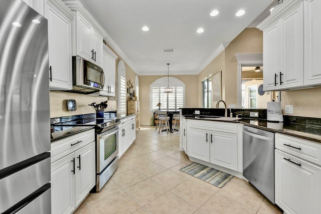 kitchen with white cabinets, appliances with stainless steel finishes, ornamental molding, and a healthy amount of sunlight