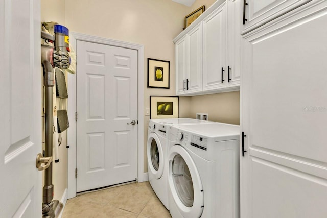 clothes washing area with washer and clothes dryer, cabinets, and light tile patterned floors