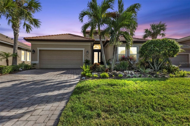 mediterranean / spanish house featuring a garage and a yard