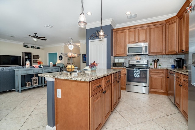 kitchen with stainless steel appliances, light stone counters, ornamental molding, ceiling fan, and a kitchen island