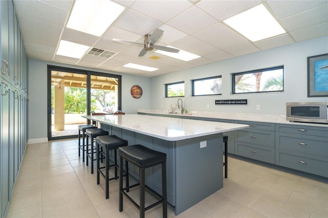 kitchen featuring a kitchen bar, a paneled ceiling, sink, and a kitchen island