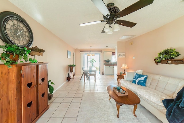 living room featuring ceiling fan with notable chandelier, a textured ceiling, and light tile patterned floors