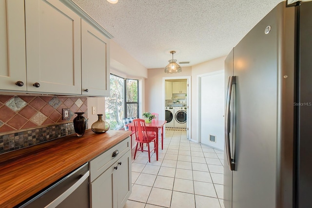 kitchen with hanging light fixtures, decorative backsplash, wood counters, appliances with stainless steel finishes, and separate washer and dryer