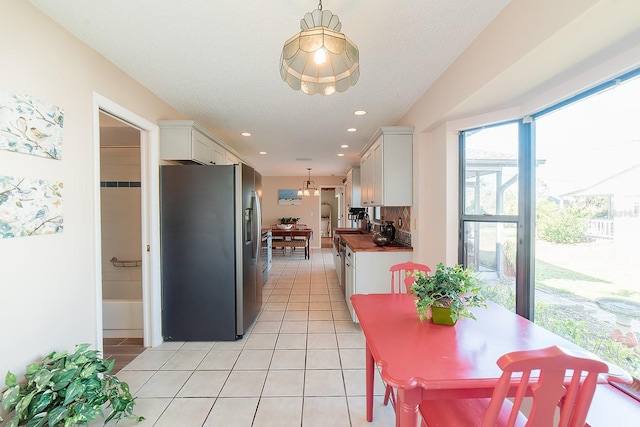 kitchen with white cabinets, butcher block counters, stainless steel refrigerator with ice dispenser, and hanging light fixtures