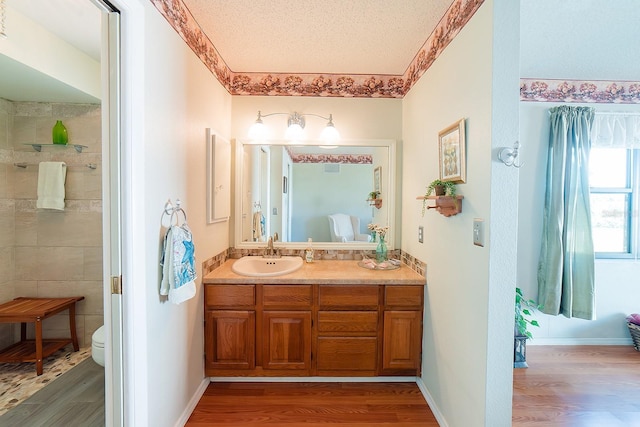 bathroom with toilet, wood-type flooring, vanity, and a textured ceiling