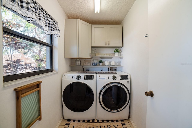 clothes washing area with a textured ceiling, cabinets, washing machine and clothes dryer, and light tile patterned floors