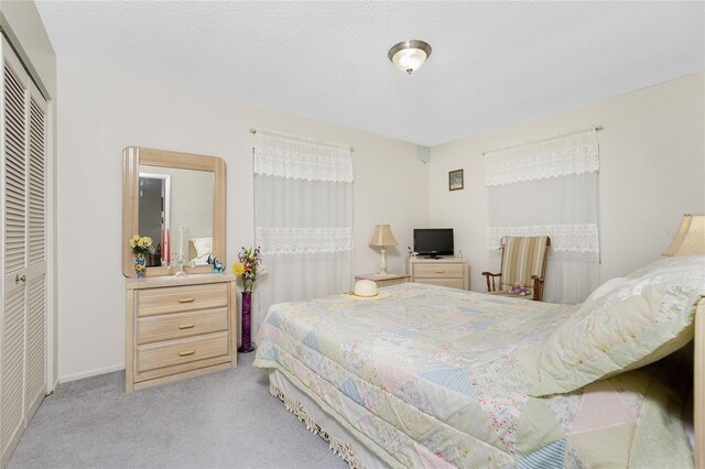 bedroom featuring light carpet, a closet, and a textured ceiling