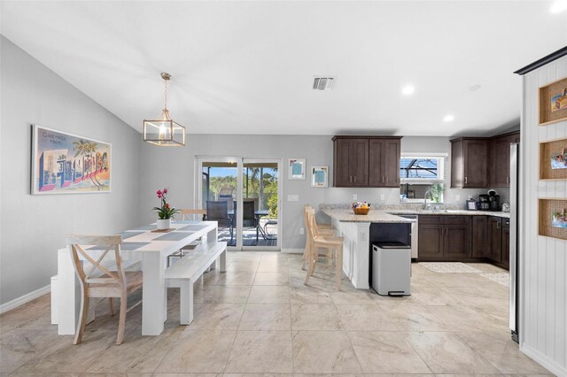 kitchen with a kitchen breakfast bar, sink, hanging light fixtures, vaulted ceiling, and dark brown cabinets