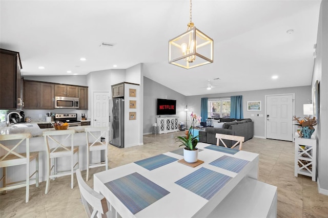 tiled dining room featuring ceiling fan with notable chandelier, lofted ceiling, and sink